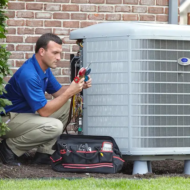 Lincoln Heating & Air HVAC technician checking refrigerant levels on an outdoor Carrier AC unit in Springfield, IL