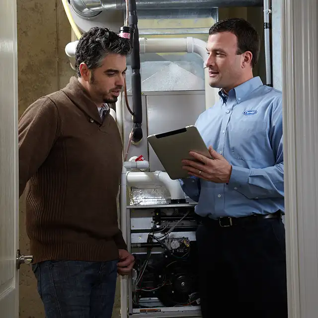 Lincoln Heating & Air technician reviewing Carrier furnace inspection results with a homeowner on a tablet in Springfield, IL